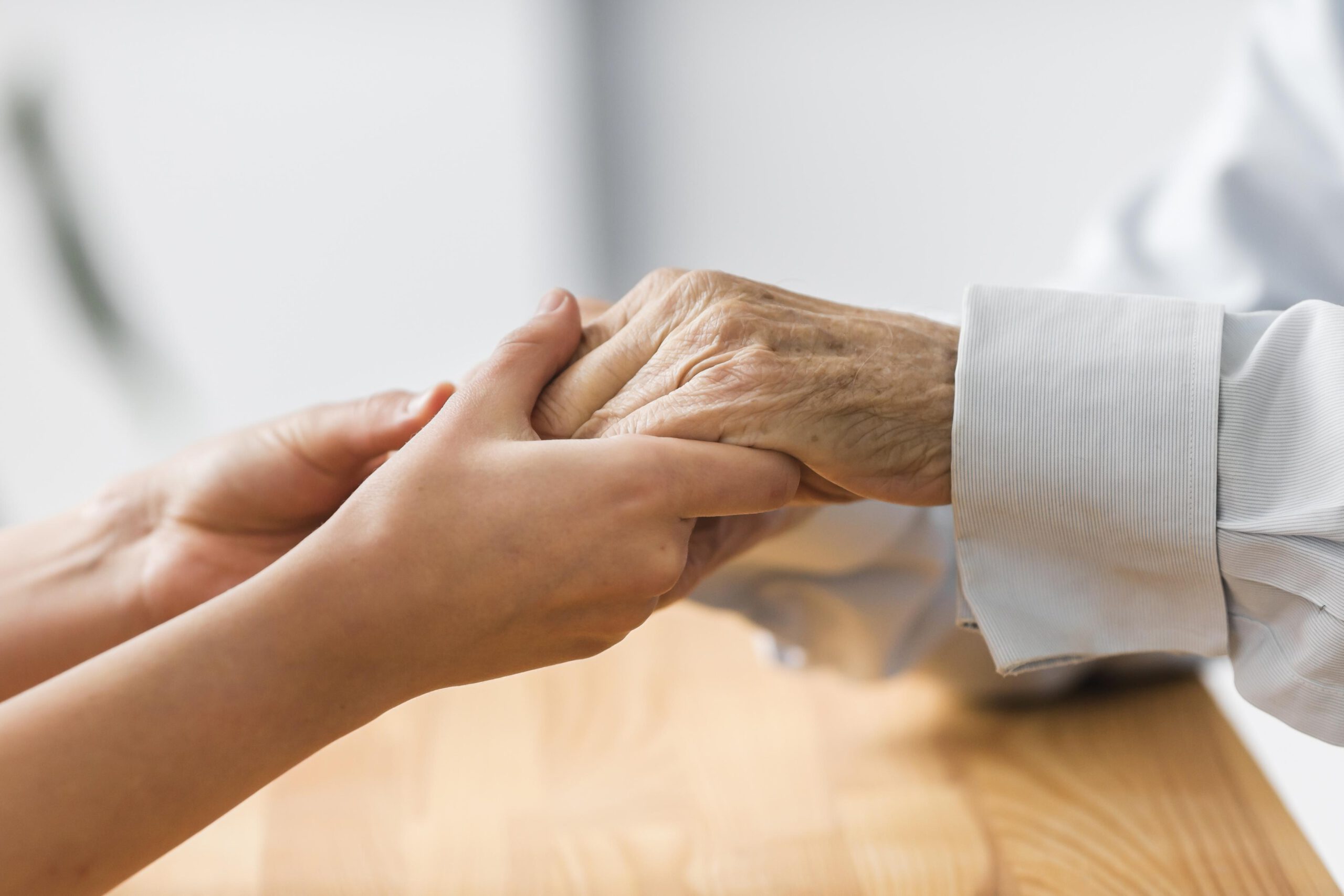 Eine jüngere Hand hält behutsam die Hand einer älteren Person